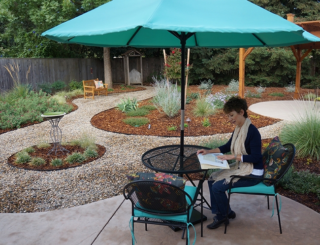 Ria de Grassi of Davis reads a gardening book in her pollinator garden in this 2015 image. (Photo by Katie Hetrick, then of the UC Davis Arboretum and Public Garden)