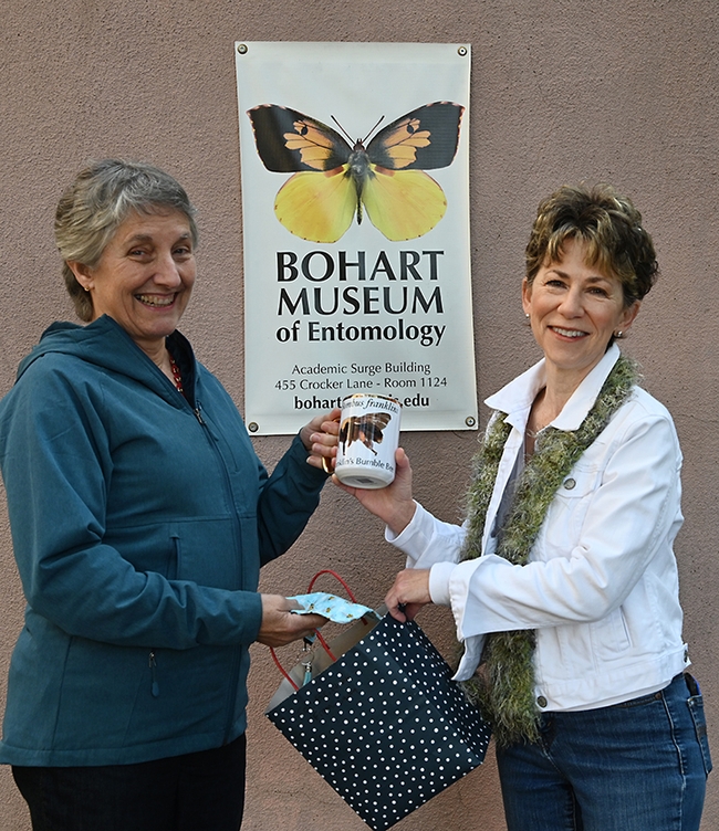 Lynn Kimsey (left), director of the Bohart Museum of Entomology, presents a prized coffee cup with an image of Franklin's bumble bee  to Ria de Grassi. (Photo by Kathy Keatley Garvey)