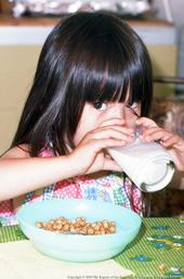 Toddler-age girl drinking milk from a glass.