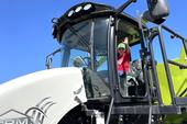 A boy sits in the cab of a harvester