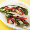 Chicken pita pocket with spinach leaves and red bell pepper.