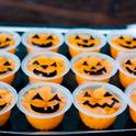 Orange fruit cups with jack-o-lantern faces drawn on the plastic.