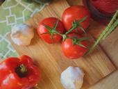 Tomatoes, garlic, and a pepper displayed on a cutting board.