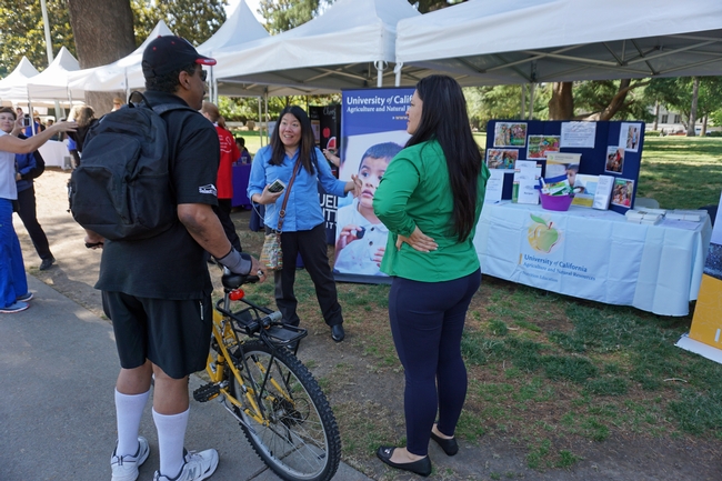 UC ANR marketing and communications specialist Suzanne Morikawa, center, fills in a visitor about EFNEP's role in the community.