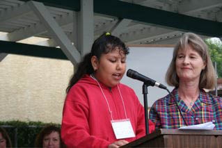 A fourth-grade student reads her winning garden essay as Linda Hahn looks on.