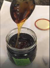 Honey drips from a spoon held above a jar.