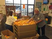 Two food bank volunteers sort oranges.