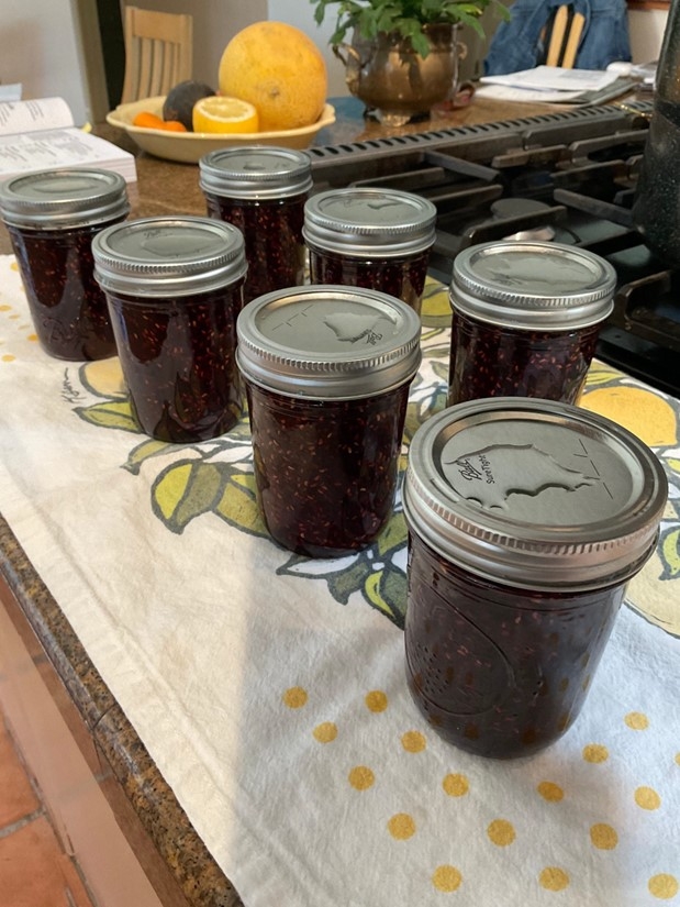7 jars of jam resting on towel on a counter.