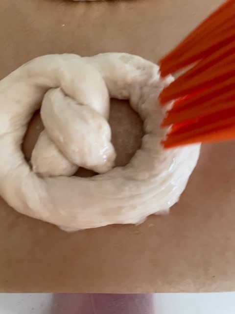 Brushing sugar water onto shaped pretzel