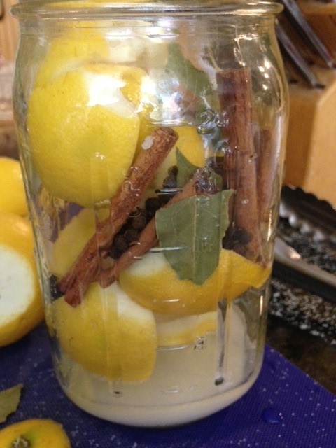Sterilized jar packed with lemons, salt, and dried spices-peppercorns, cinnamon sticks, bay leaves