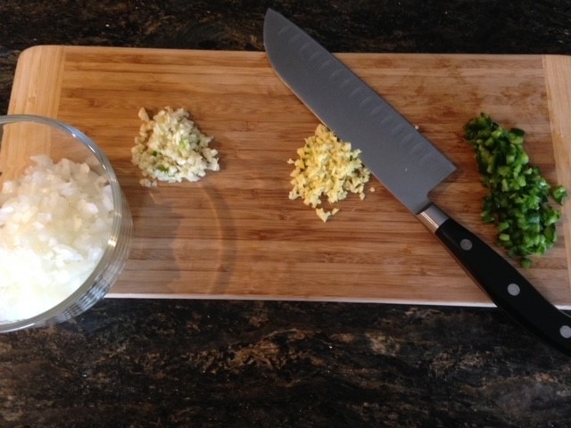 Chopped aromatics and peppers on cutting board