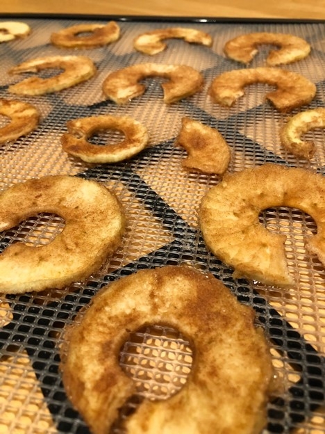 light brown apple rings on a dehydrator tray