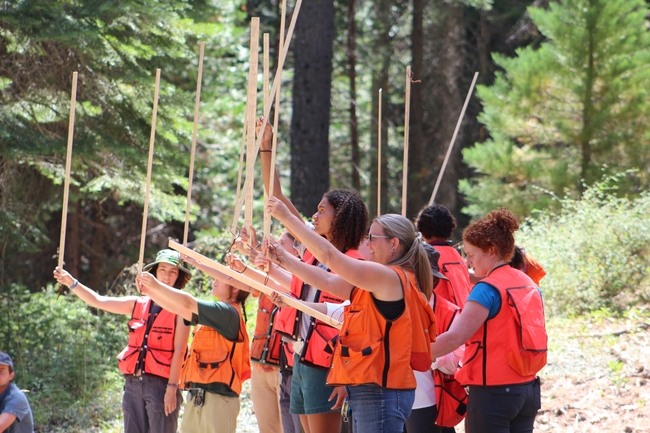 UC ANR's Susie Kocher and Katie Reidy leads Tuesday's ‘forestry skills' section. Here, students learn how to use a California tree stick. Photo credit: Karina Bencomo.