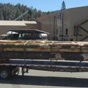 Flat bed log truck arriving at Trinity River Lumber with the new sawmill building in the background,