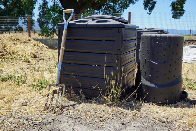 A commercial home compost bin, right, and a bin improvised by cutting holes and the bottom out of an ordinary plastic trash can.