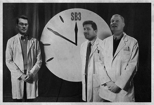 Image of Alex, Karl and Dave standing near a clock pointing to Site Builder 3