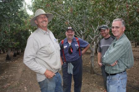 Trunk-shaking pistachio harvester trials: the usual suspects: Erick Nielsen of Nielsen Enterprises, Terry Tompkins of Gold Coast Hydraulics, Robert of Nielsen Enterprises, and Dr. Uriel Rosa
