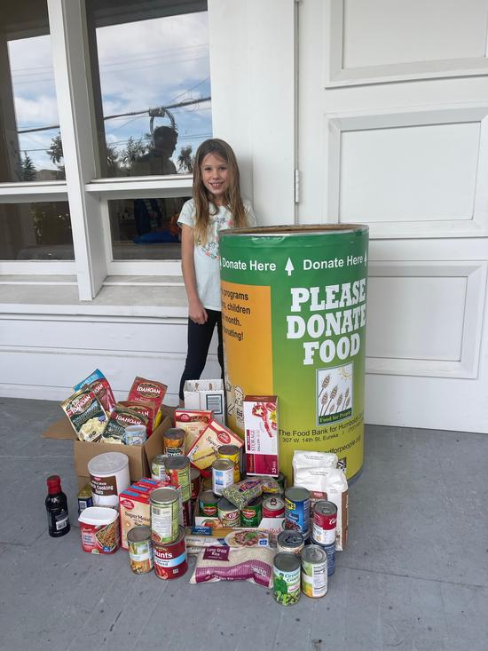 Ferndale Youth standing by food donation container. Canned and dried food is on the ground in front