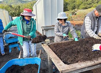 Volunteers mix soil for seeding spring and summer edibles.
