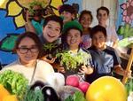 Picture of boys and girls holding up vegetables they grew