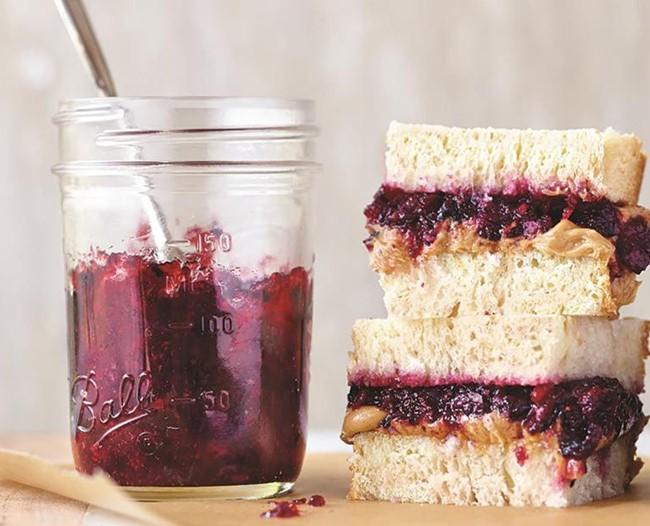 Jar of jam with a peanut butter and jam sandwich