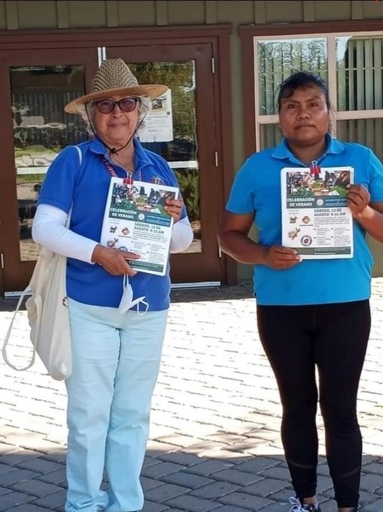 Two women holding flyers about farmers markets