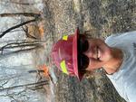 Lenya Quinn-Davidson is wearing a red hard hat with a prescribed fire buring in the background in an oak woodland in the winter