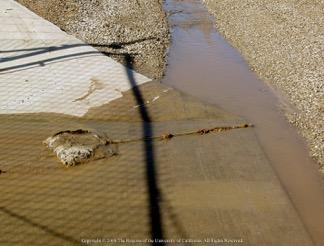 Fig. 12. Polyacrylamide (PAM), a flocculant held in anchored bag, removes sediment from runoff entering retention basin. Photo: A. Storm & J.P. Newman