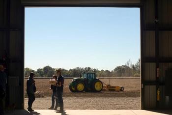 Researchers talk while a tractor moves across a field at the UC Davis Russell Ranch Sustainable Agriculture Facility in 2016
