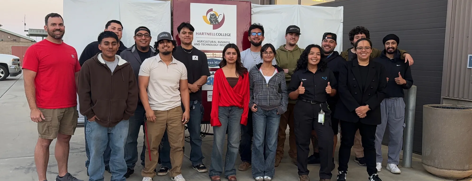 A farm robotics team stands in front of a backdrop that reads Hartnell College