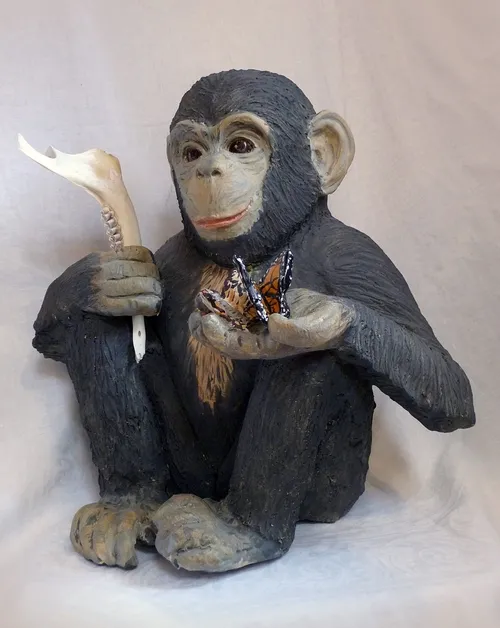 DARWIN--This piece at the Pence Gallery, Davis, is the work of ceramic artist Nuala Creed of Petaluma. Of her art she says: “As he sits holding butterflies and the jawbone of an animal, the chimp gazes directly at the viewer. His offering to us, his next of kin, is his curiosity of the natural world. His intelligence is shown by his inquisitiveness. His name is Darwin, in honor of Charles Darwin, whose work helped us realize that we humans are not above nature, but are of nature. The chimp may be asking us