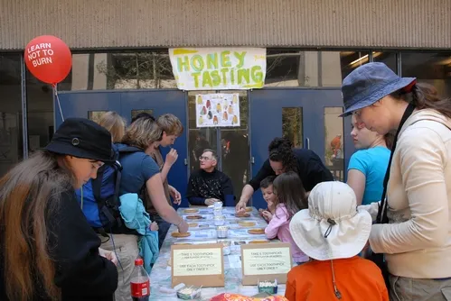 COOPERATIVE EXTENSION APICULTURIST Eric Mussen (center) answers questions about honey at the annual honey tasting table at Briggs Hall, UC Davis. (Photo by Kathy Keatley Garvey)