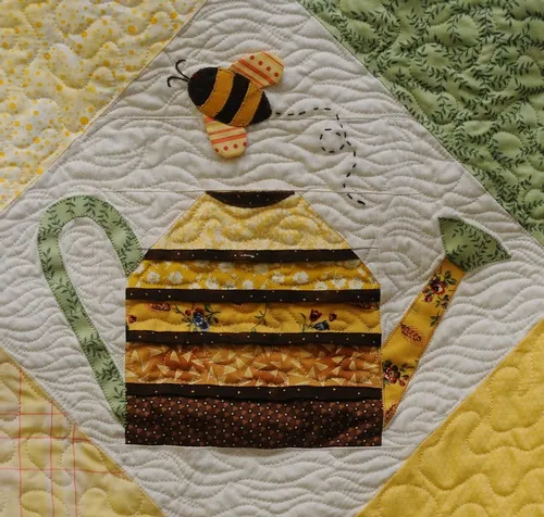 CLOSE-UP of a honey bee and a plant watering can on a quilt at the Dixon May Fair. This quilt is the work of Shirley Geertson of Vacaville. (Photo by Kathy Keatley Garvey)