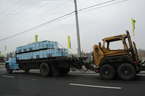 A SURE SIGN OF SPRING--A truck loaded with bee hives tows a forklift as it travels through Sacramento. The forklift will alleviate the movement and placement of the hives in a soggy orchard. (Photo by Kathy Keatley Garvey)