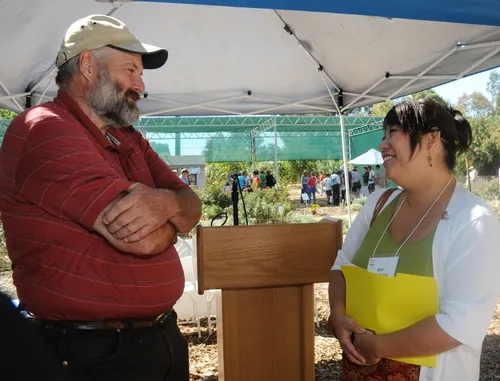 BEEKEEPER Frank Pendell of Pendell Apiaries, Stonyford, Calif., vice president of the California State Beekeepers' Association, chats with Dori Sera Bailey, director of consumer communications, Häagen-Dazs and Dreyer’s Grand Ice Cream. In the back are visitors touring the garden. (Photo by Kathy Keatley Garvey)
