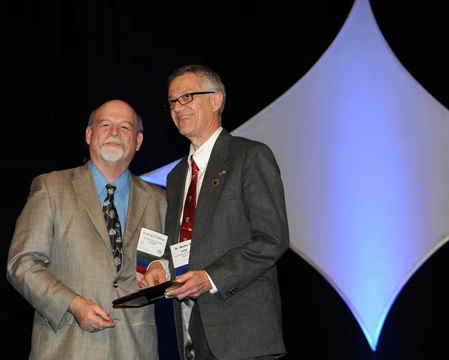 UC Davis pofessor Walter Leal (right) receives the Nan-Yao Su Award from ESA President Ernest Delfosse. (Photo by Kathy Keatley Garvey