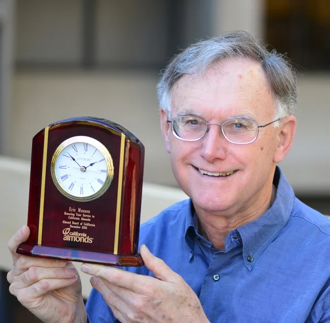 Extension apiculturist (emeritus) Eric Mussen with his engraved clock from the Almond Board of California. (Photo by Kathy Keatley Garvey)