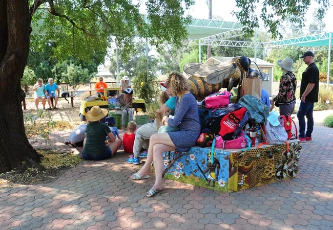 First graders, school officials and parents from Peregrine School cluster around a bee sculpture at UC Davis Häagen-Dazs Honey Bee for a "Kids and Bees" program. (Photo by Kathy Keatley Garvey)