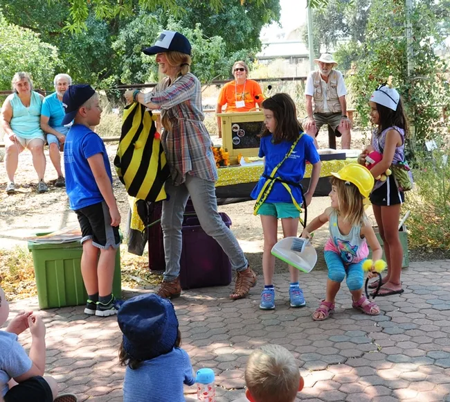 Sarah the Bee Girl outfits a first grader with a forager costume for correctly answering a question about foragers. (Photo by Kathy Keatley Garvey)