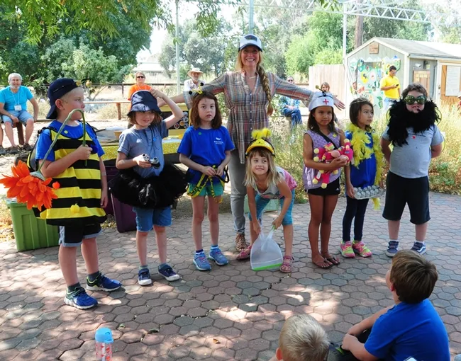 After Sarah the Bee Girl (back) read a book about bees, she quizzed them, and those with the correct answers were given props depicting those bees. These youngsters represent (from left) a forager, a scout bee, a house bee, a nurse bee, the queen bee and a drone. (Photo by Kathy Keatley Garvey)