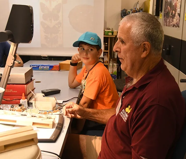 Delsin Russell, 7, of Vacaville, who wants to become an entomologist, is fascinated by the butterfly/moth demonstration by entomologist/curator Jeff Smith. (Photo by Kathy Keatley Garvey)