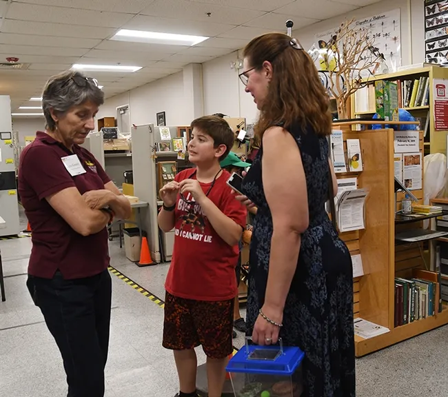 Delsin Russell, 8, of Vacaville, wearing a T-shirt, "I Like Big Bugs; I Cannot Lie," asks a question of Lynn Kimsey, director of the Bohart Museum. At right is Delsin's mother, Beth Russell, who related that Delsin wants to become an entomologist. (Photo by Kathy Keatley Garvey)
