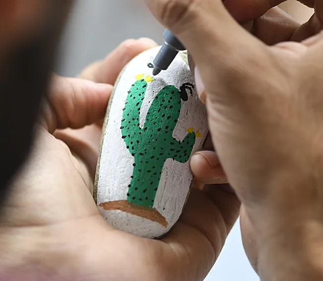 Entomologist Joel Hernandez adds the finishing touches on a rock painted by his wife, Melissa Cruz, the outreach coordinator for the UC Davis Arboretum and Public Garden. (Photo by Kathy Keatley Garvey)