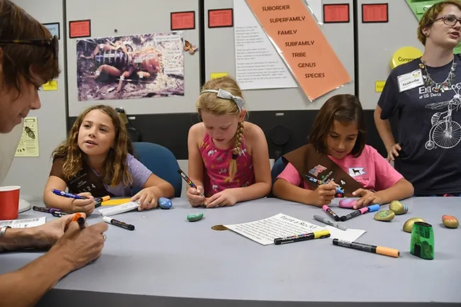 Members of Brownie Troop 3124 of Sacramento participated in the rock painting. In the foreground is leader Suzanne Enslow. The Brownies (from left) are Antonia Fedele-Mcleod, Adair Enslow, and Amelia Pacheco, all seven years old. At right is activity leader Isabelle Gilchrist, a UC Davis entomology major. (Photo by Kathy Keatley Garvey)
