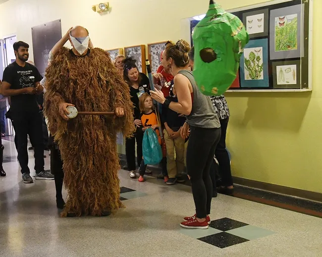 UC Davis forensic entomologist Robert Kimsey, dressed in a ghillie suit, is blindfolded by Tabatha Yang, Bohart education and outreach coordinator and game coordinator. (Photo by Kathy Keatley Garvey)