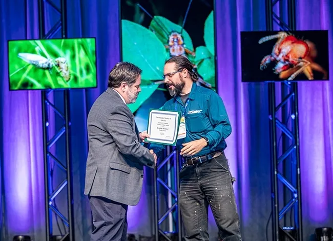 UC Davis doctoral candidate Brendon Boudinot walks on stage to receive the John Henry Comstock Award from ESA President Robert Peterson of Montana State University. (ESA Photo)