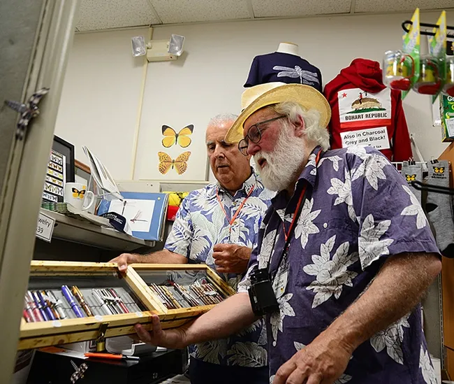 Jeff Smith (left) who curates the Bohart Museum's Lepidoptera collection, shows Robert Michael Pyle the pens he crafted from wood, available in the Bohart gift shop. (Photo by Kathy Keatley Garvey)