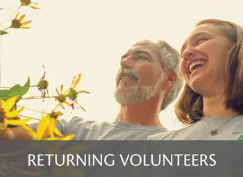 Man and woman smiling with a yellow flower graphic; text at the bottom reads ‘Returning Volunteers.’