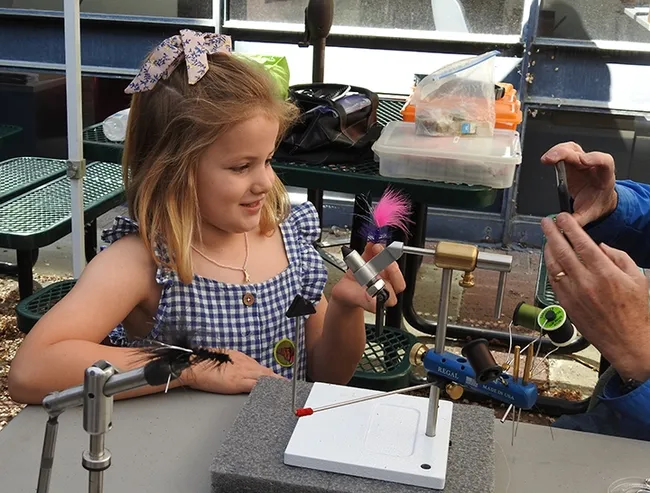 Ella Eich proudly displays the pink fly created by Paul Berliner of the Fly Fishers of Davis. (Photo by Kathy Keatley Garvey)
