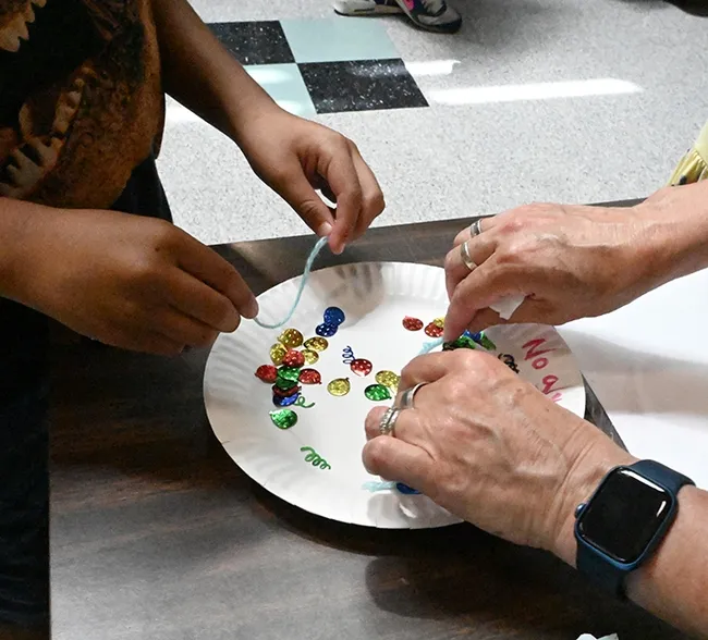 A participant strings yarn across the confetti to see if it sticks. (Photo by Kathy Keatley Garvey)